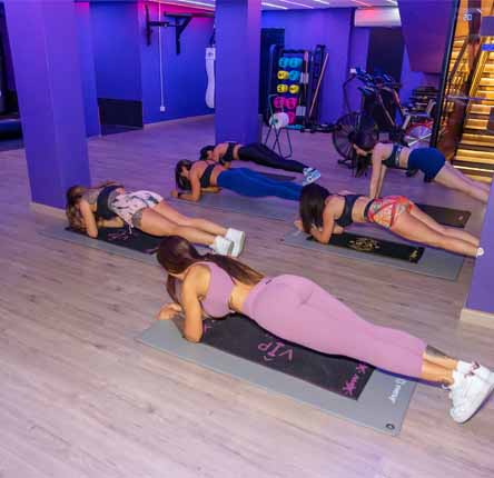 grupo mujeres entrenan plancha abdominal gimnasio