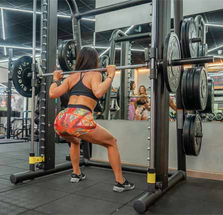 mujer entrena squat maquina fitness